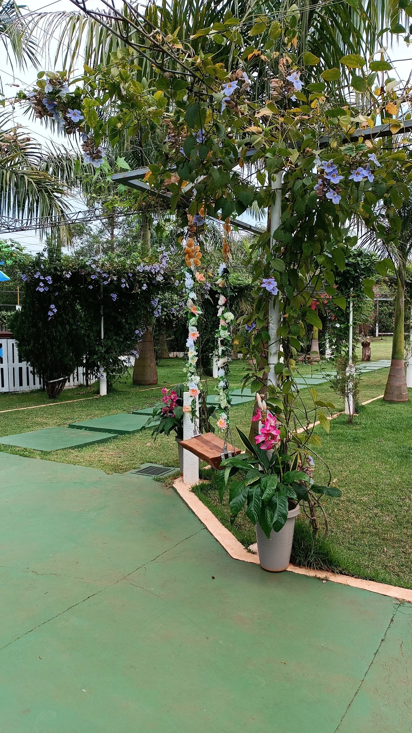 Jardín con pérgola, flores y césped verde